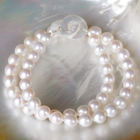 Klassische Süßwasser Perlenkette von Gellner mit weißen Ming Perlen auf Perlmutt liegend