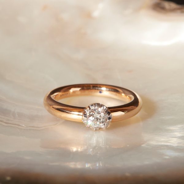 Extravaganter Schmuckwerk Alpenring Solitaire aus Rosegold mit Bruchkante Weißgold und 040ct Brillant auf Perlmutt liegend