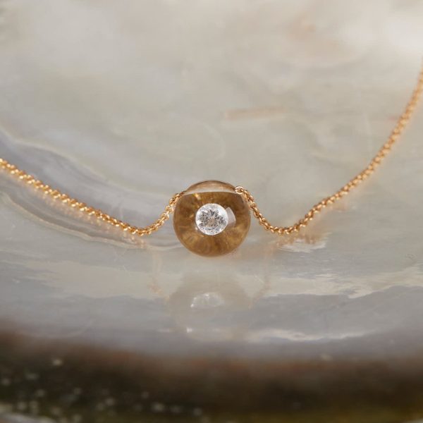 Kurze Schmuckwerk Glasklar Kette Gelbgold mit schwebendem Diamant 0060ct auf Perlmutt liegend