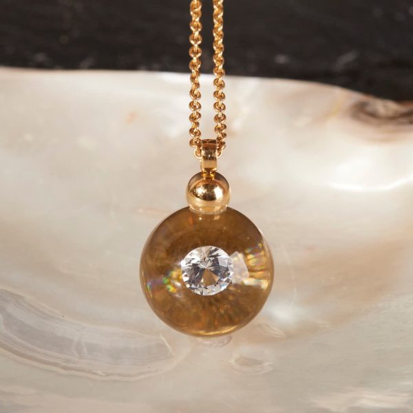 Lange Schmuckwerk Glasklar Kette Gelbgold mit Brillant 030ct mit Gelbgold hinterlegt auf Perlmutt fotografiert