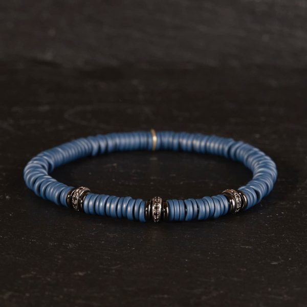 Lässiges Herren Armband aus blauen Keramikringen und geschwärzten Weißgoldringen auf Spiralkern aufgezogen von Silhouette auf Schwarz fotografiert