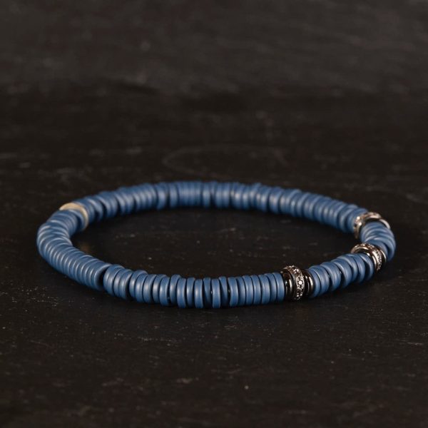 Lässiges Herren Armband aus blauen Keramikringen und geschwärzten Weißgoldringen auf Spiralkern aufgezogen von Silhouette auf Schwarz fotografiert